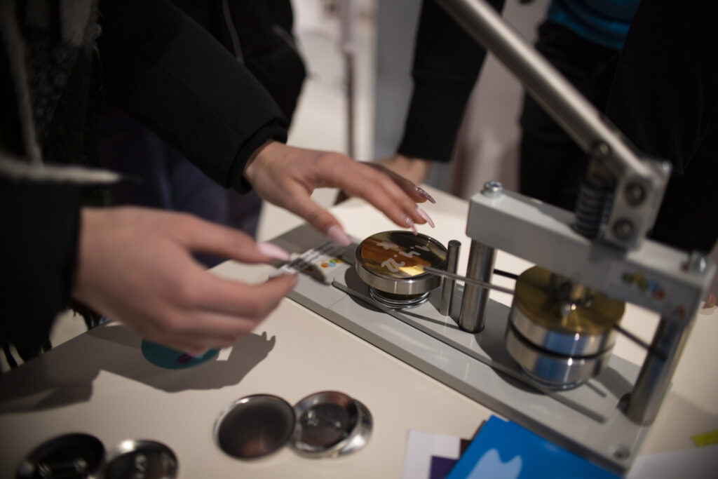 Hände arbeiten an der Buttonmaschine