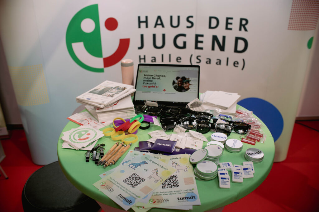 Messetisch mit kleinen Gewinnen, im Hintergrund Logo des Hauses der Jugend