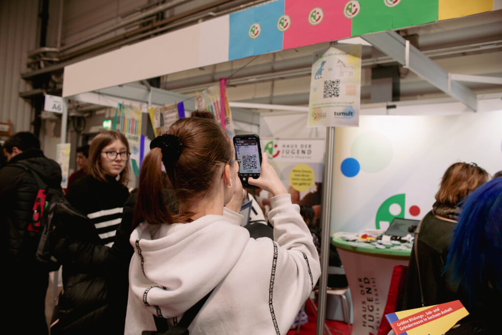 junger Mensch scannt QR-Code am Messestand ab
