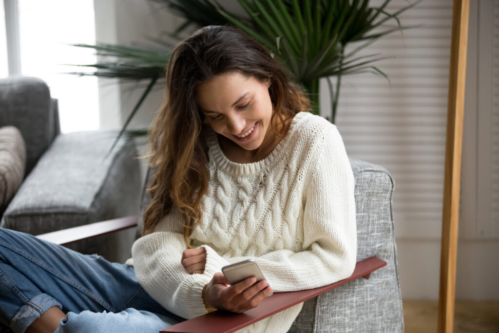 Smiling happy millennial woman holding smartphone